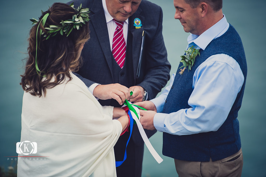 Elope to Ireland in dublin on a cliff at the Howth lighthouse walk bride and groom ceremony having a handfasting ceremony. North Carolina and Florida Cliffside Wedding in Ireland