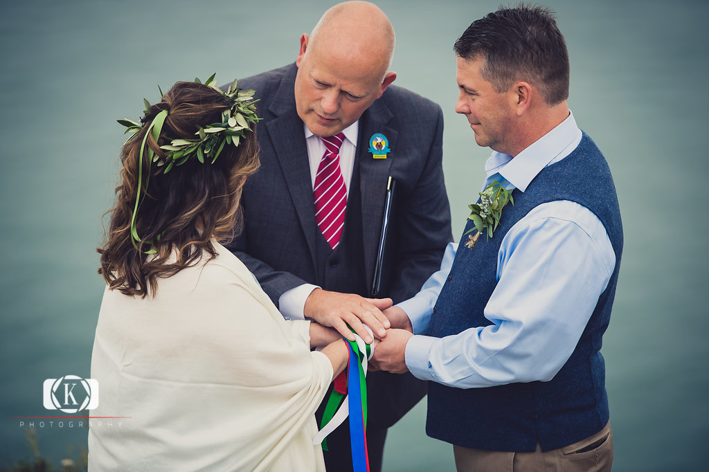 Elope to Ireland in dublin on a cliff at the Howth lighthouse walk bride and groom ceremony having a handfasting ceremony