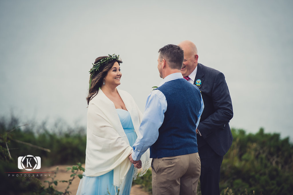 Elope to Ireland in dublin on a cliff at the Howth lighthouse walk bride and groom ceremony having a giggle with Tom Farrell from spiritual ceremonies