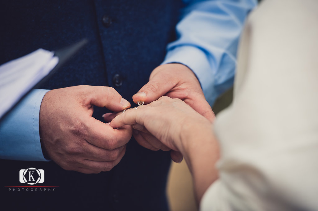 Elope to Ireland in dublin on a cliff at the Howth lighthouse walk bride and groom ceremony putting the ring on the finger