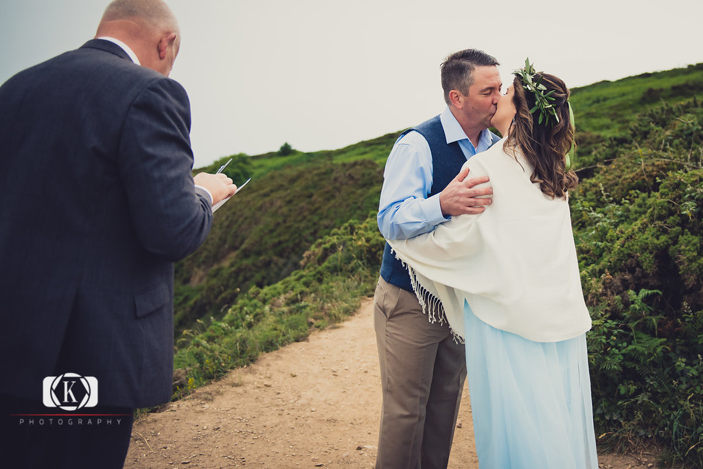 Elope to Ireland in dublin on a cliff at the Howth lighthouse walk bride and groom ceremonyhaving a kiss