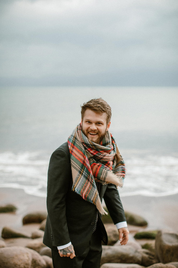 Coastal intimate Wedding in Ireland. Here is the groom wearing a scarf and smiling 