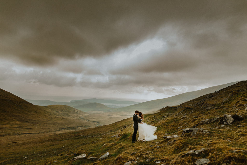 The newly weds on top of a mountain holding each other at their intimate wedding in Ireland 