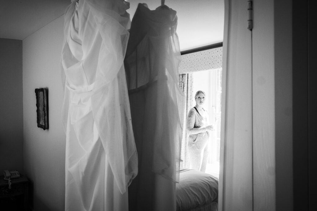 bride looking a wedding drtess hanging up before her Spring Elopement in West Cork at Bantry House 