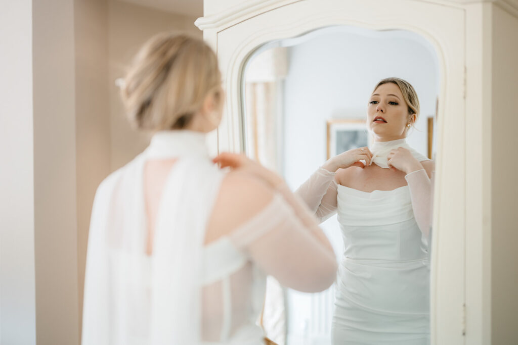 our second bride of the day getting ready in front of the mirror wearing a white dress before An Elegant Spring Elopement in West Cork at Bantry House brought to to you by Elope To Ireland 