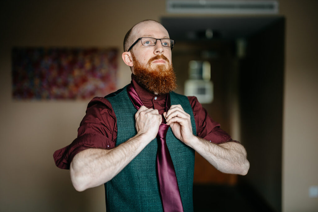 Groom buttons up his waistcoat before he his elopement in ireland with Elope To Ireland