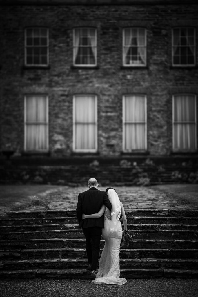 Wedding couple in a black and white photo closely embracing out maor house in Ireland