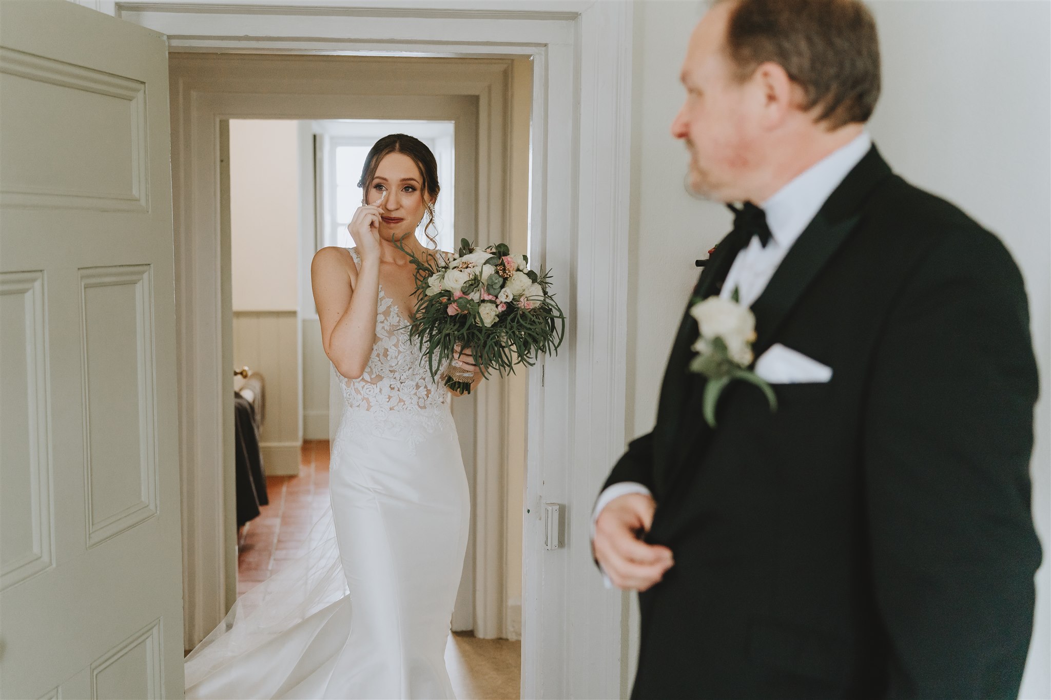 bride meeting dad wiping away tears from her eyes