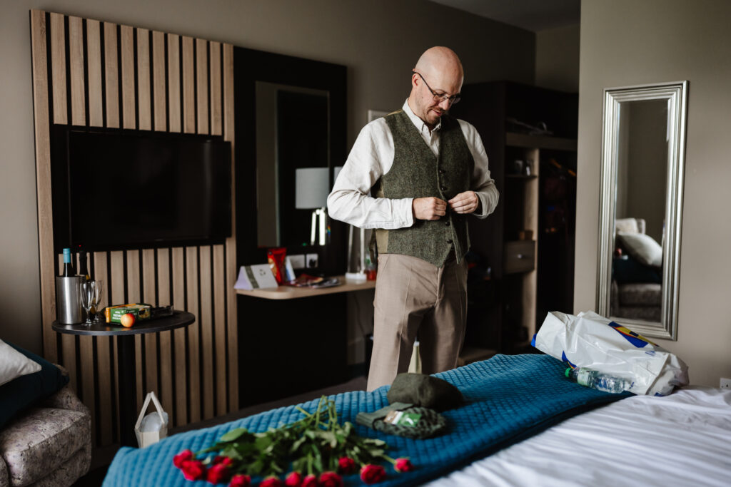 grrom getting ready putting on his waistcoat before elopement in killarney national park 