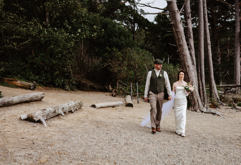 the bride and groom walking to their ceremony on the beach