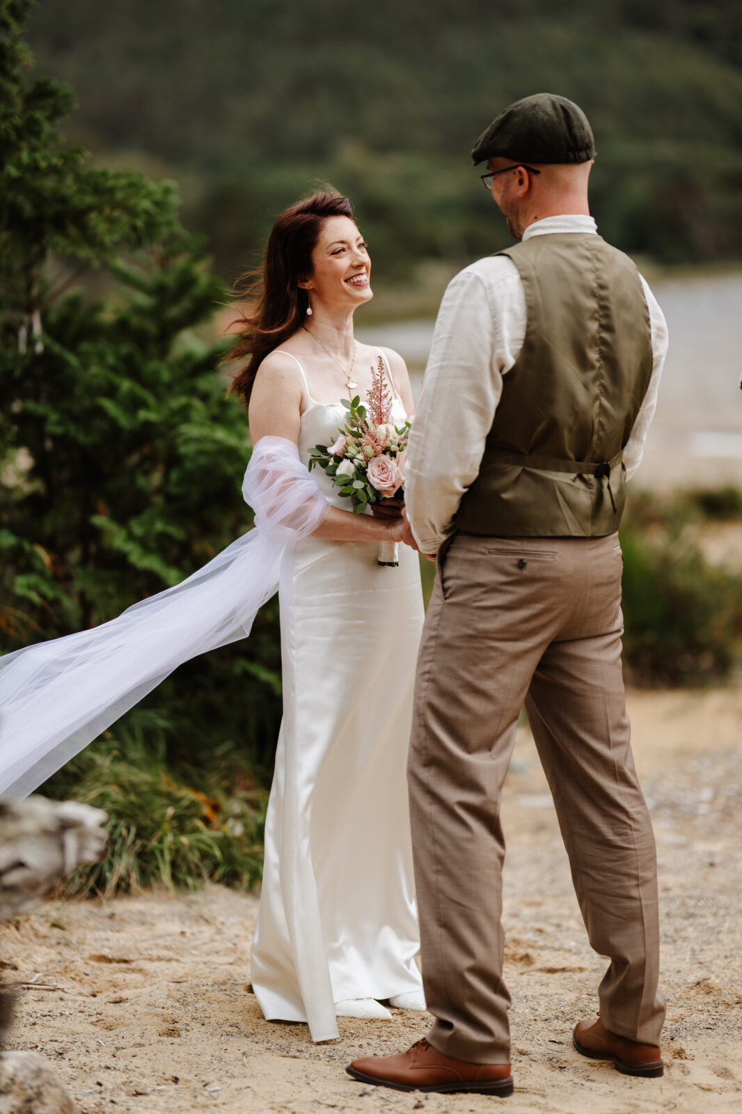 bride and groom hold hands with the bride the tail of the brides dress blowing in the wind