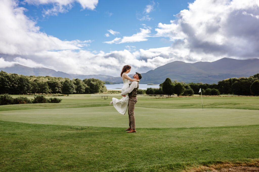 groom lifts the bride up with an amzing background landscape 